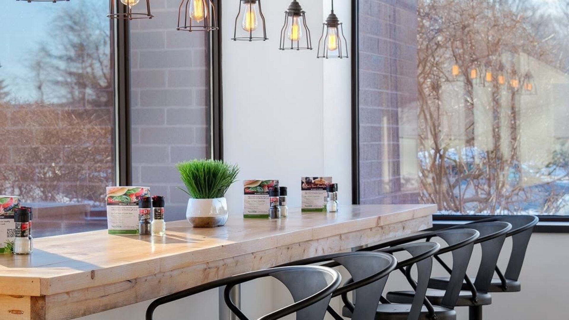 A chic bar seating area at a cafe with overhead lighting and tall stools
